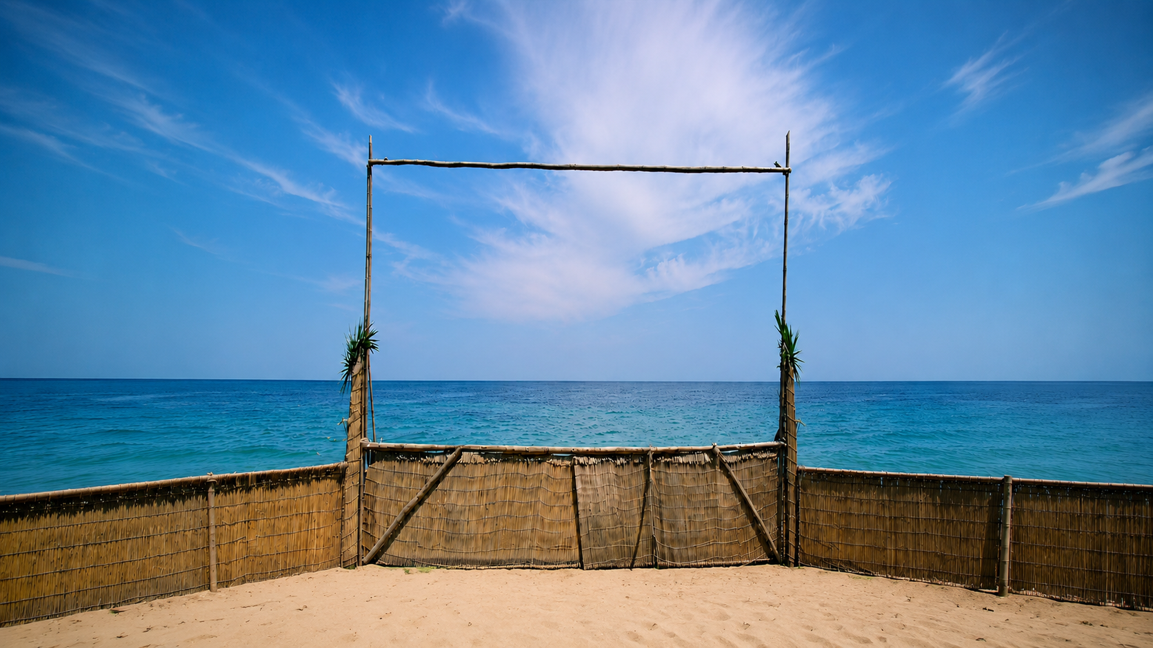 Strand mit Blick aufs Meer: Zwischen zwei Bambusstangen mit Querbalken spannt sich eine Leinwand, auf der der Stream läuft